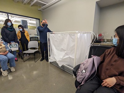 people in a conference room looking at a wheelchair sized portable wash station