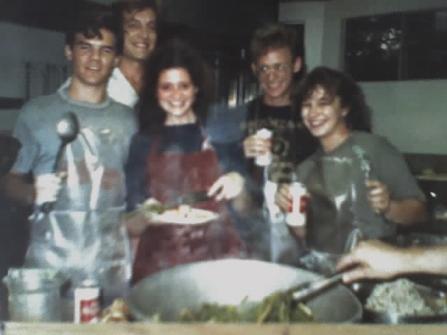 several young people gathered around a giant bowl of steaming food. they are drinking old milwaukee beers