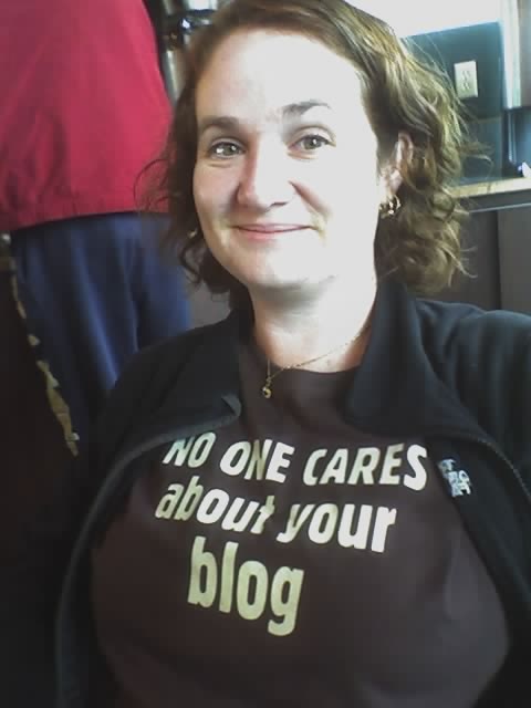 white woman with a wry expression wearing a tshirt that reads "no one cares about your blog"