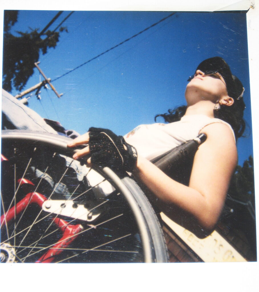 photo of young liz in a cambered sporty red quickie in 1993, leather hat and gloves, also huge muscles wow 