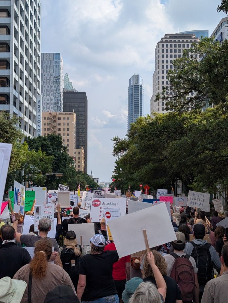 view down austin's main downtown street, congress ave, of a big crowd marching with signs
