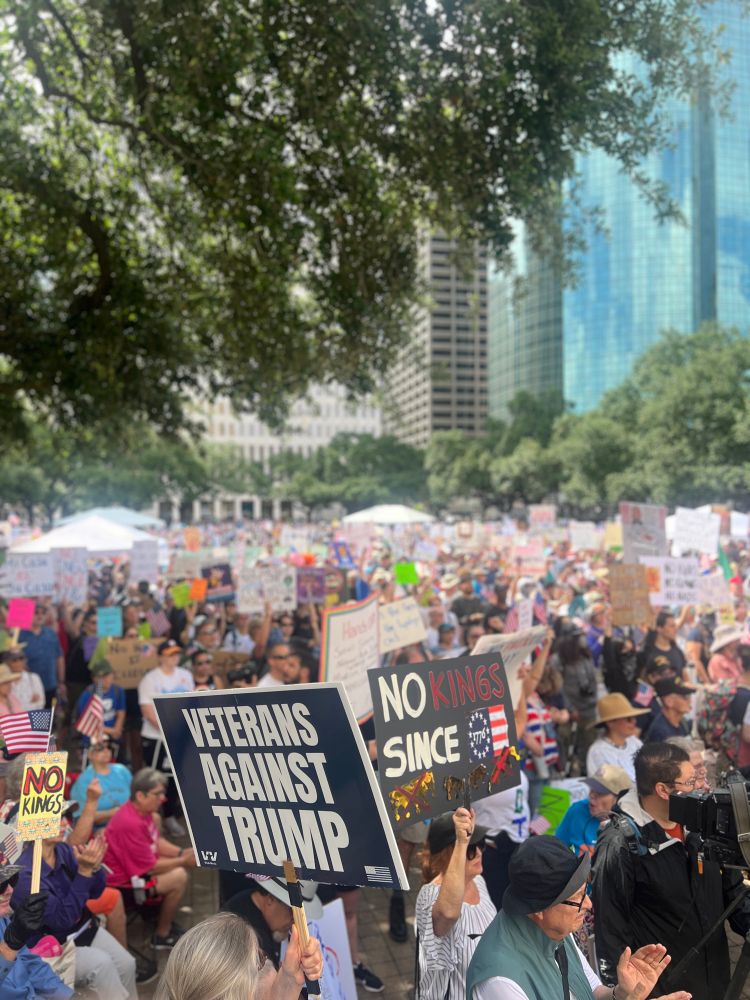 photo from within a crowd of  baseball hatted houstonians with signs, likely everyone is covered in sweat