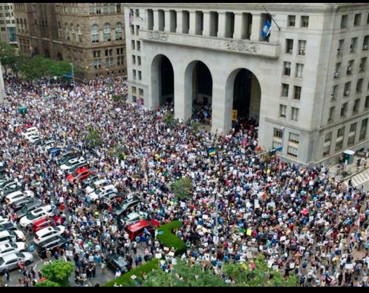 a more clear aerial shot of the crowd in front of an official looking building in pittsburgh