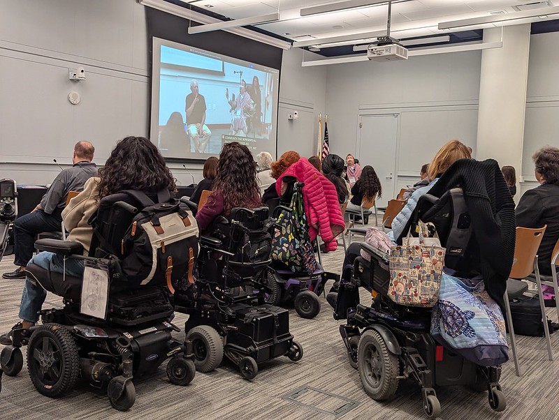 several powerchair users facing the conference speaker Dr victor pineda 