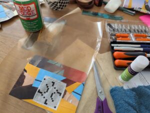 scissors, glue, wax paper, and an envelope covered in bits of paper